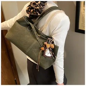 Détail du sac cabas vert foncé avec surpiqûres et breloque cœur léopard sur la bandoulière