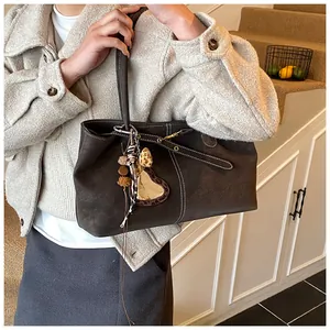 Détail du cabas marron vintage avec surpiqûres blanches et breloque léopard en cœur
