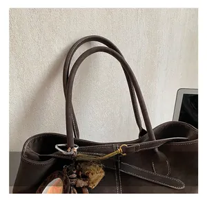 Détail du sac cabas marron avec des coutures contrastées blanches et des poignées rondes