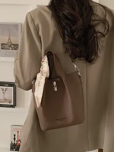 Minimalist dark brown lychee leather bucket bag with silver twist lock and silk scarf decor