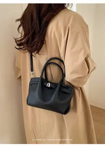 Minimalist black pebble leather bucket bag shown as a shoulder bag on a model