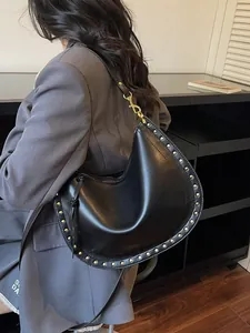 Black leather saddle tote bag with silver rivets shown from a stylish side view angle