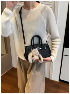 Detailansicht einer schwarzen Ledertasche mit Silberbeschlägen und Plüsch-Hasenanhänger