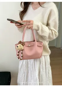 Pink lychee leather bucket bag detail with cute plush puppy charm and metal buckle