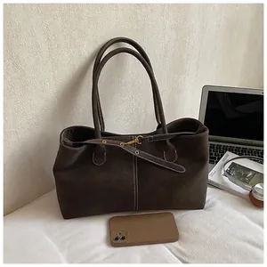 Détail d'un sac cabas marron foncé avec coutures contrastées et boucle à œillet en métal