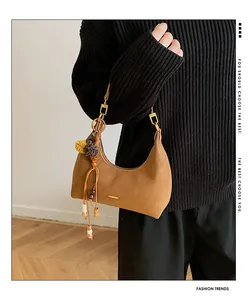 Detail of caramel hobo bag with gold hardware and bohemian charm on black sweater
