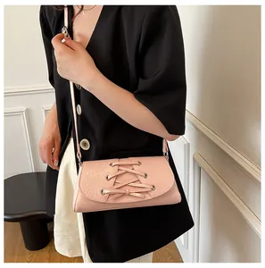Detail of pink baguette bag with corset lace-up design and silver eyelets on a model