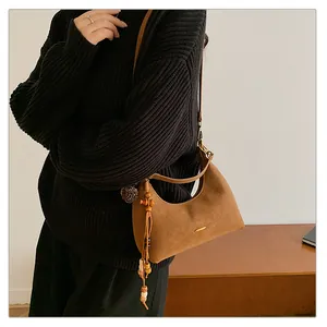 Detail of brown suede hobo bag with vintage wooden beads and tassel accessory