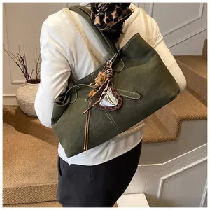 Vue détaillée du sac cabas en daim vert olive avec coutures blanches et pendentif cœur
