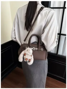 Detail der dunkelbraunen Leder Baguette Tasche mit silbernem Drehverschluss und Hasenanhänger