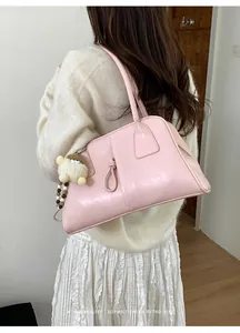 Sac fourre-tout rose en cuir avec détail noué et breloque alpaga porté par mannequin