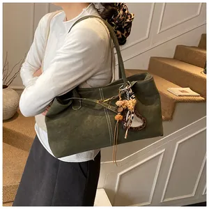 Détail du sac cabas en daim vert olive avec coutures contrastées et breloque léopard
