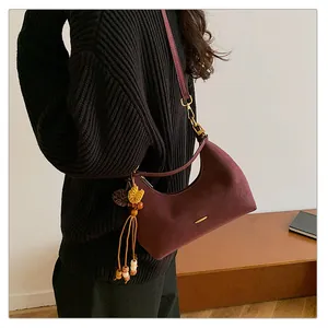Close-up of wine red suede hobo bag with vintage gold hardware and a tassel charm