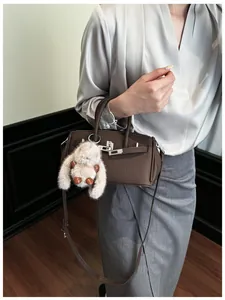 Details einer dunkelbraunen Tasche aus genarbtem Leder mit Schnalle und Plüsch-Hase