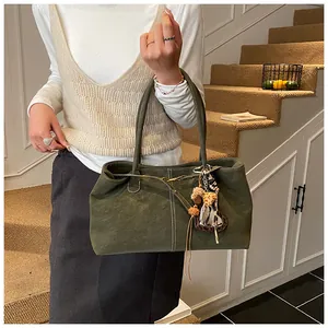 Gros plan du cabas vert olive en daim mat avec breloques porté par une femme à l'épaule