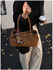 Détail d'un sac cabas marron en daim avec pendentif en cœur et pompon imprimé animal