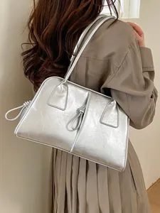 Grand sac cabas argenté avec détail de cordon noué porté par un mannequin chic