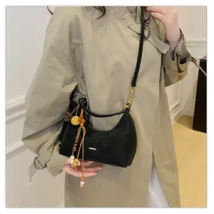Close-up of black crescent shoulder bag with colorful bead tassel and yellow pom-pom