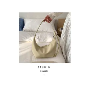 Detailed macro view of the cream hobo bag showing its fine lychee grain leather texture