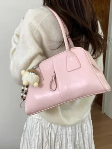 Sac fourre-tout rose en cuir avec nœud décoratif et charm en peluche porté par un modèle