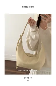Close-up of cream crescent hobo bag featuring knotted shoulder strap and soft leather texture