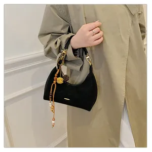 Close-up of black matte crescent bag with beaded charm and gold hardware detail