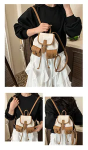Detail view of mini canvas backpack with brown leather trim and multi-pocket design