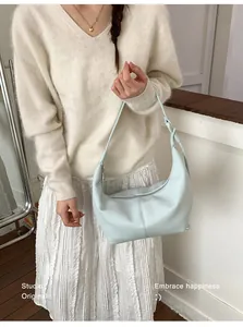 Detail of light blue hobo bag showing pebbled leather texture and side knot decoration