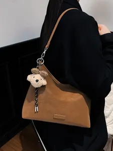 Braune Wildleder-Einkaufstasche mit MUJU & BAGS-Logo und Plüschbär-Anhänger an der Schulter