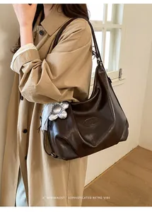 Detail der dunkelbraunen Hobo-Tasche aus Kunstleder mit silbernem Blumenanhänger und Logo