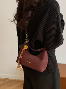 Retro burgundy matte leather dumpling bag with gold logo and bead tassel on a model