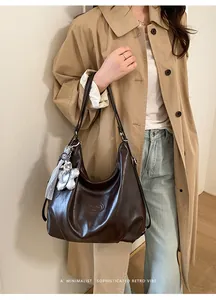 Detail der dunkelbraunen Leder-Hobo-Tasche mit Silberbär-Anhänger und Logo-Prägung
