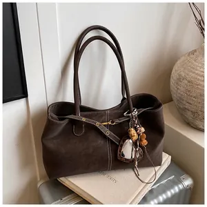 Détail du grand sac cabas marron vintage avec sangle à œillets et breloque cœur léopard