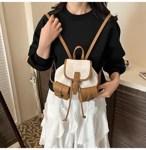 Detail of canvas and brown leather mini backpack with metal buckle closures and drawstrings