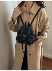 Detail of a grey denim checkered mini backpack with black leather trim on trench coat