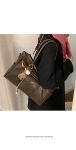 Détail d'un sac cabas rétro marron foncé avec poche avant et pendentif cheval en peluche