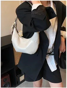 Close-up of white crescent bag with quilted stitching and LOVE & DESIRE text detail