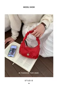 Detail of red pleated handbag with bow knot and silver heart pendant on white dress