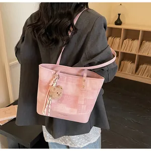 Detail of pink canvas tote bag with leather patchwork and bear charm on shoulder