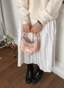 Macro view of pink pleated handbag with silver heart pendant and bow detail