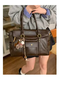 Détail du sac cabas marron vintage avec poche à boucle et breloque cheval en peluche