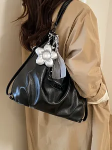 Große schwarze Leder-Shopper-Tasche mit Blumenanhänger und Tuch auf der Schulter