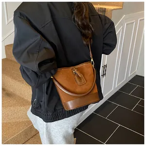 Detail der dunkelbraunen Beuteltasche mit goldenen Beschlägen auf Treppenstufen