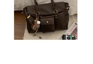 Détails du sac cabas en cuir marron foncé avec boucle dorée et accessoire en peluche