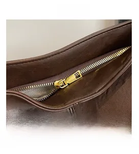 Detail showing high-quality smooth gold zipper and brown leather texture on tote bag