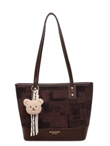 Brown geometric patterned tote bag with leather straps and plush bear charm