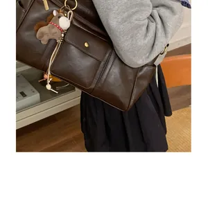 Gros plan d'un grand sac cabas marron foncé avec finition brillante et breloque poney
