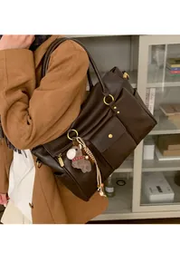 Détail du grand sac cabas en cuir marron foncé avec breloque poney et anses en métal