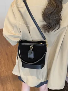 Schwarze Retro-Eimertasche aus Wildleder mit Lederbesatz und goldenen Beschlägen