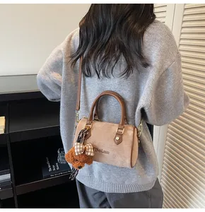 Detail of warm brown suede Boston bag with letter embroidery and a plush bear charm
